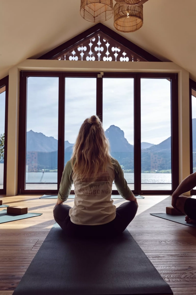 Yoga-Übung im Wellnessraum des 4‑Sterne-Hotels am Wolfgangsee mit Blick auf See und Berge