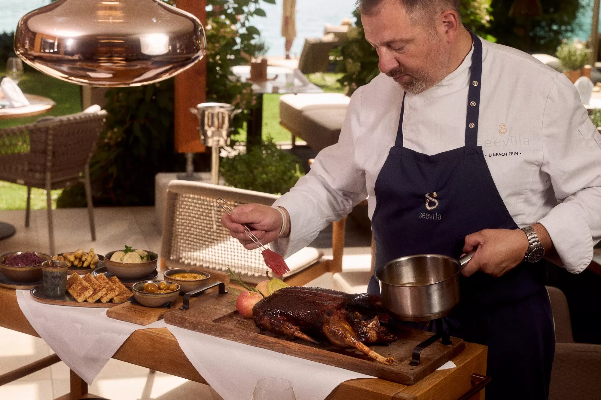 A chef with a goose at the Ledererhaus gourmet restaurant on Lake Wolfgang, serving specialties outdoors