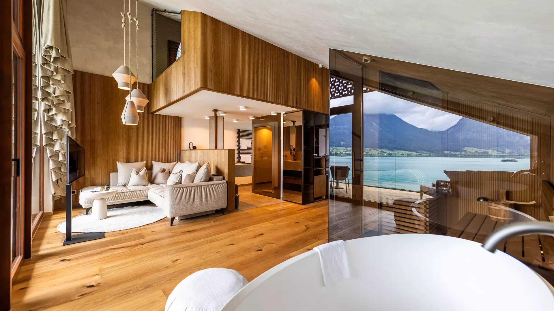 Elegantes Hotelzimmer mit Doppelbett und Blick auf den Wolfgangsee, moderne Sauna und Ruhebereich am Seeufer